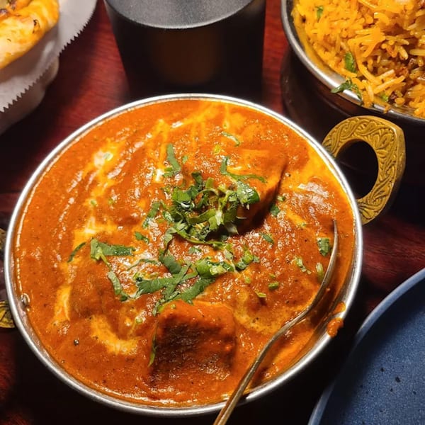 A close-up of a bowl of Indian butter chicken, garnished with fresh cilantro, at Spice Kitchen.