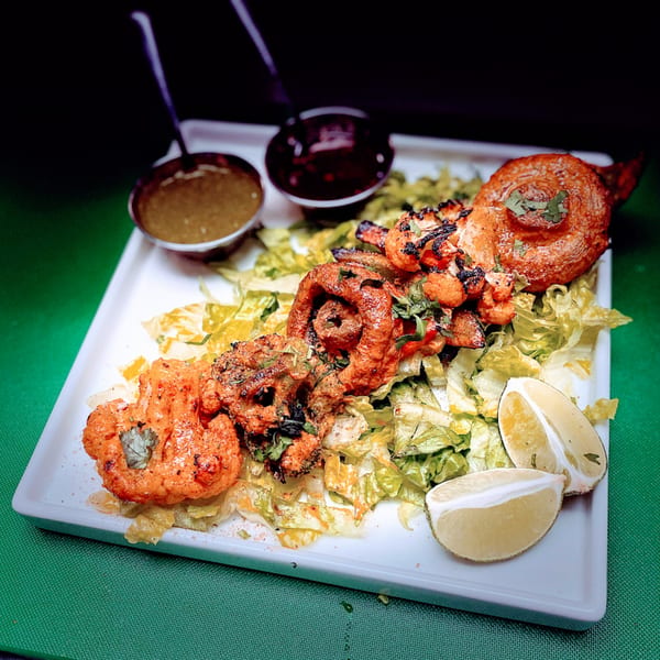 Spice Kitchen's Indian platter with grilled cauliflower, kebab, lettuce, lime, and dipping sauces.