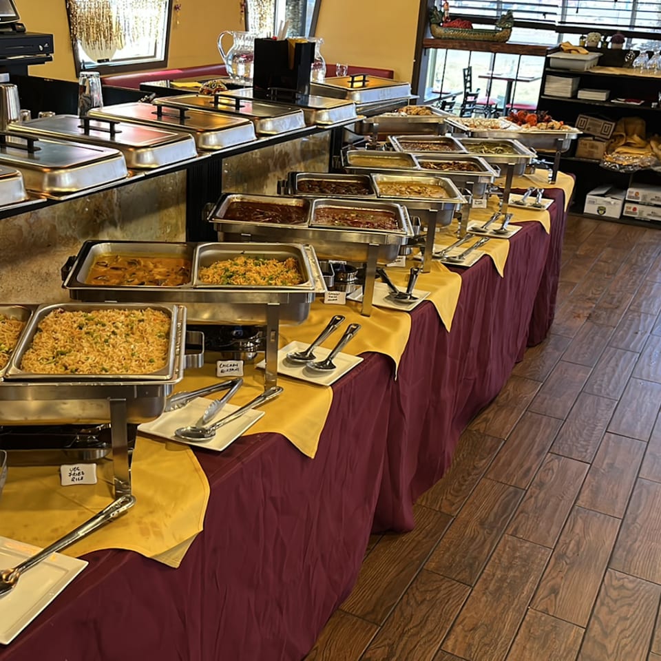 A long buffet table at Spice Kitchen with various Indian dishes in chafing dishes.