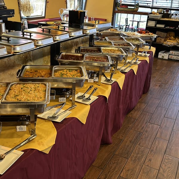 A long buffet table at Spice Kitchen with various Indian dishes in chafing dishes.
