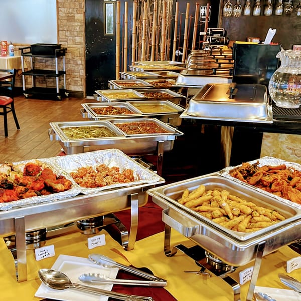 A buffet line at Spice Kitchen with various Indian dishes in silver chafing dishes.
